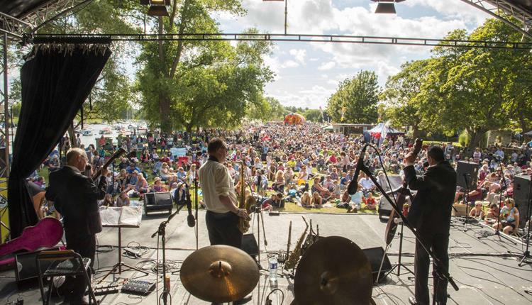 An image looking out between a jazz band towards a large crowed on a sunny day at Stompin' on the Quomps in Christchurch.